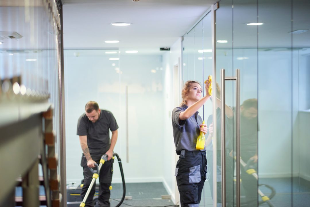 Cleaning team at work in an office with glass partitions
